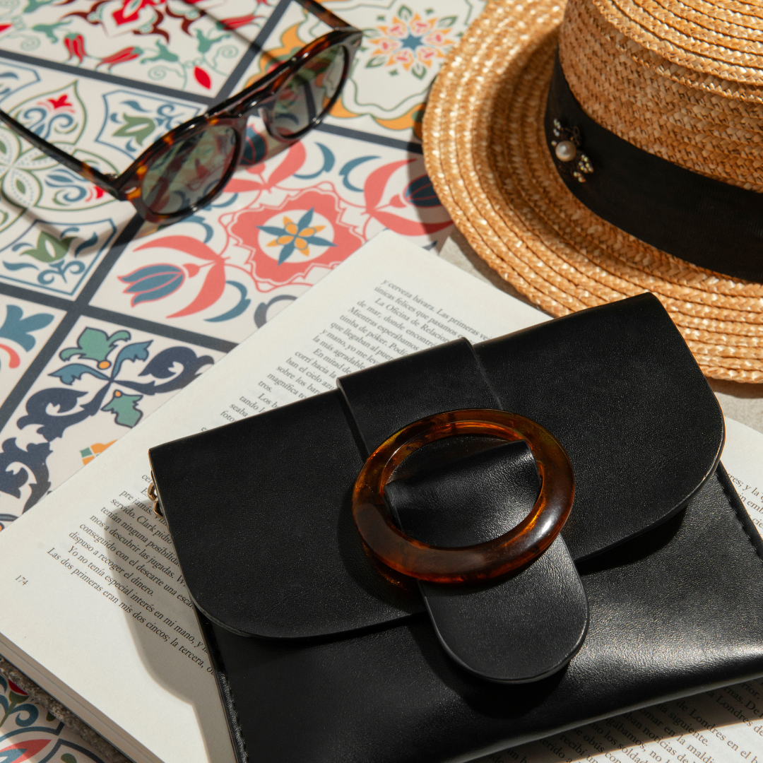 Women's fashion accessories flatlay with black handbag sunglasses and straw hat — Emmy & Ellie accessories